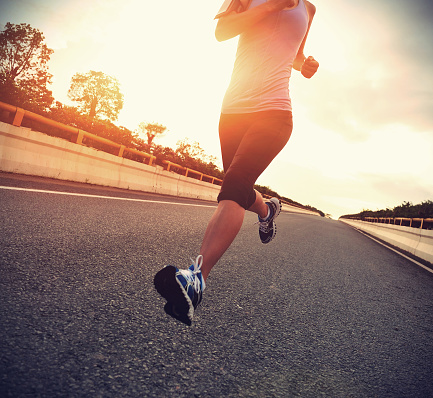 young woman runner running on city bridge road