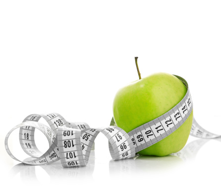 Measuring tape wrapped around a green apple