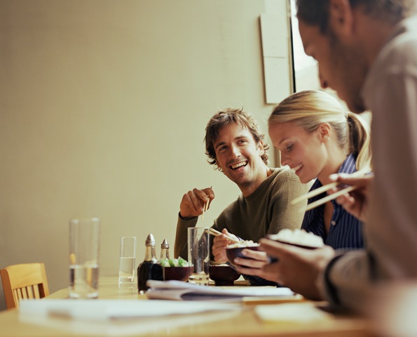 Young man having lunch with woman and man, smiling