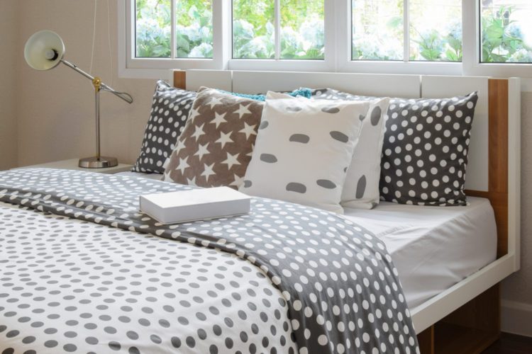 bedroom interior design with polka dot pillows on bed and decorative bedside table lamp.
